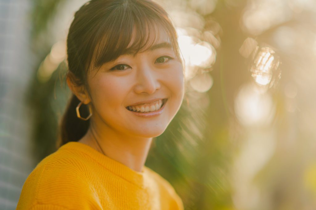 A portrait of a beautiful woman in a yellow sweater in nature on a sunny day.