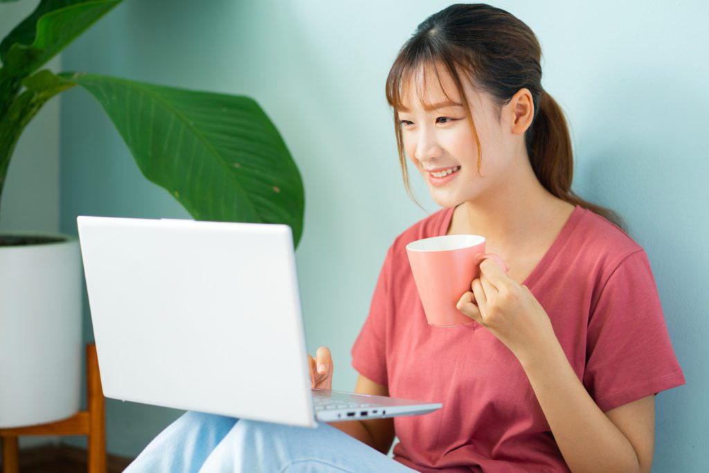 Asian businesswoman sitting on the floor using laptop to work from home